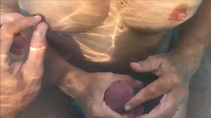 Horny naked babe giving him a hand job in the pool and gets cum covered