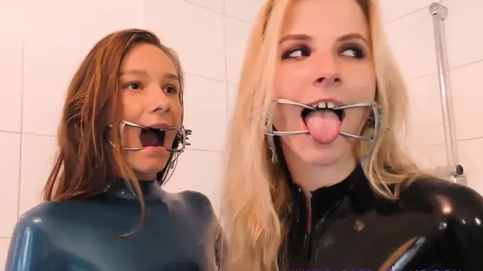 Two horny babes wearing latex and high heels making out in a nasty way